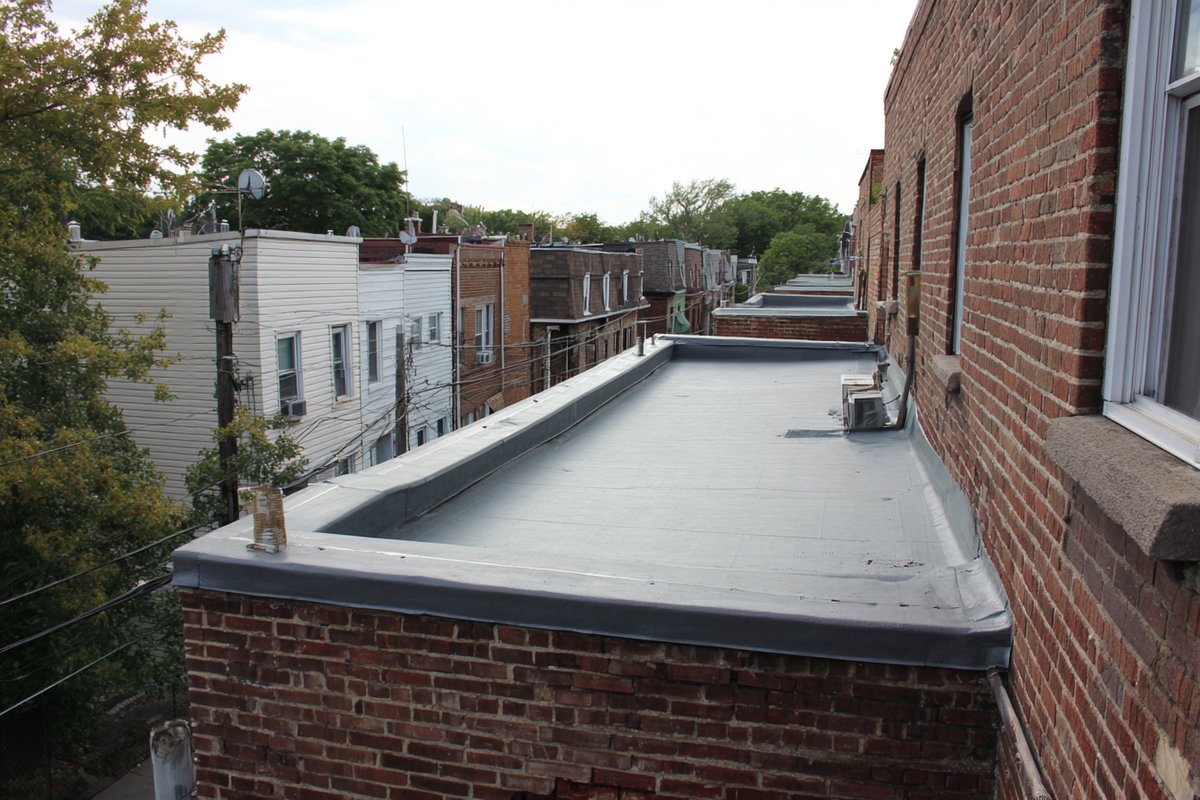 Row of flat roofs on attached Queens houses seen from a neighbouring rooftop, with the Manhattan skyline behind