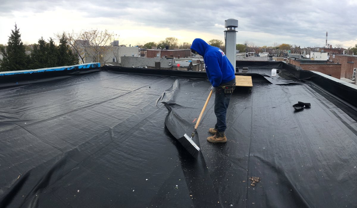 Fresh EPDM membrane being fully adhered over new polyiso insulation boards on a flat roof