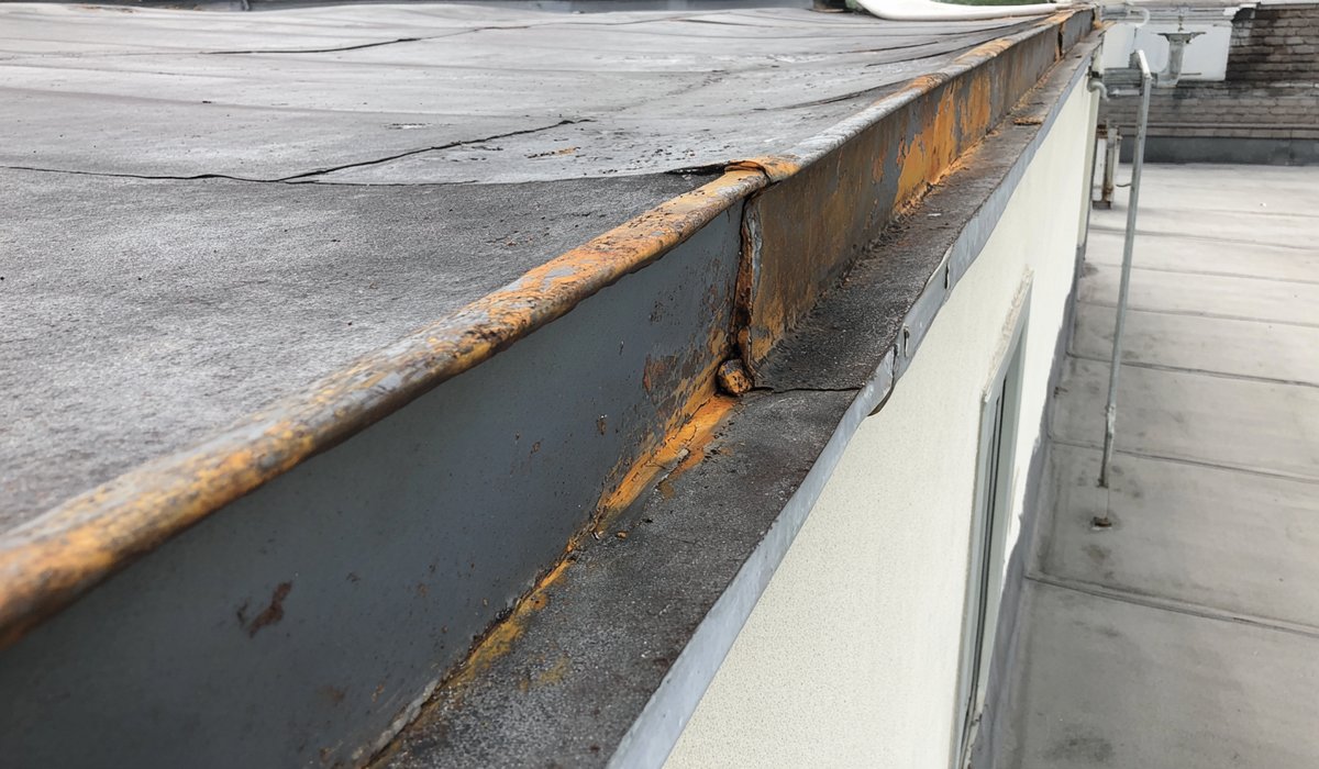 Close view of an older patched seam on a modified bitumen flat roof in Far Rockaway, with rust showing on the parapet flashing