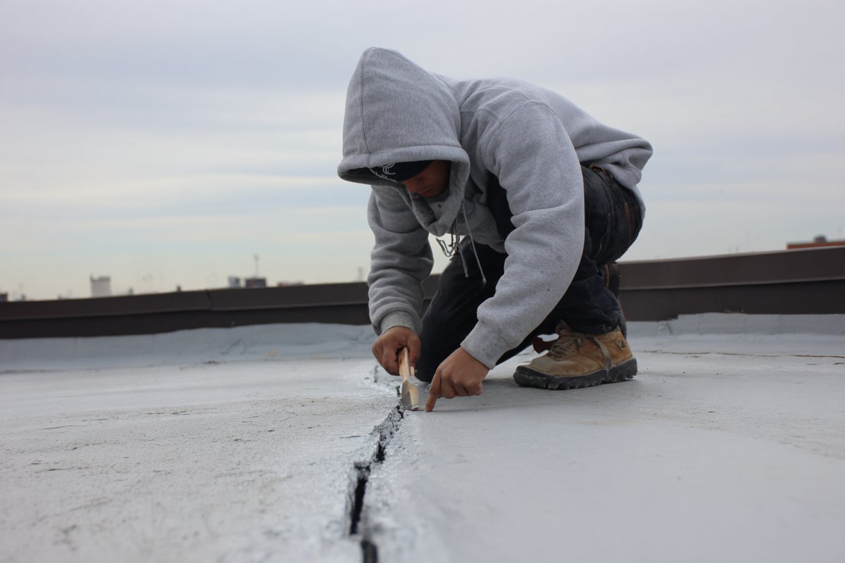 Roofer resealing a short split in a flat roof seam before it turns into a leak
