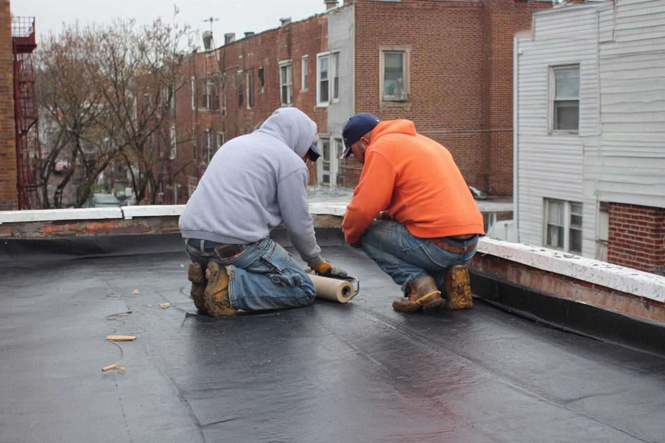Flat Roofers NY crew seaming EPDM rubber on a flat rooftop in Queens