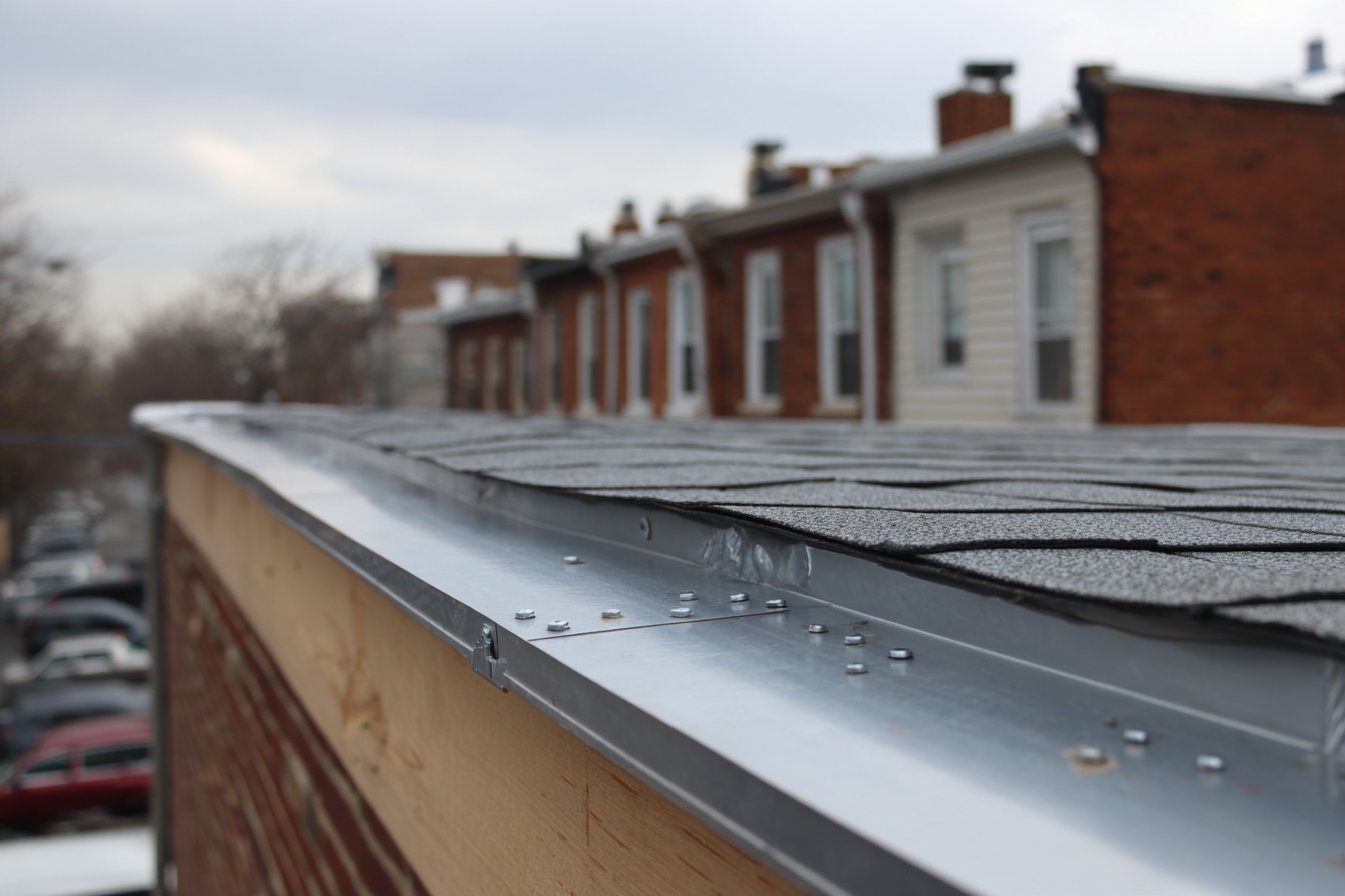 Metal drip edge fastened along a flat roof deck edge, its lower leg kicking out past the fascia