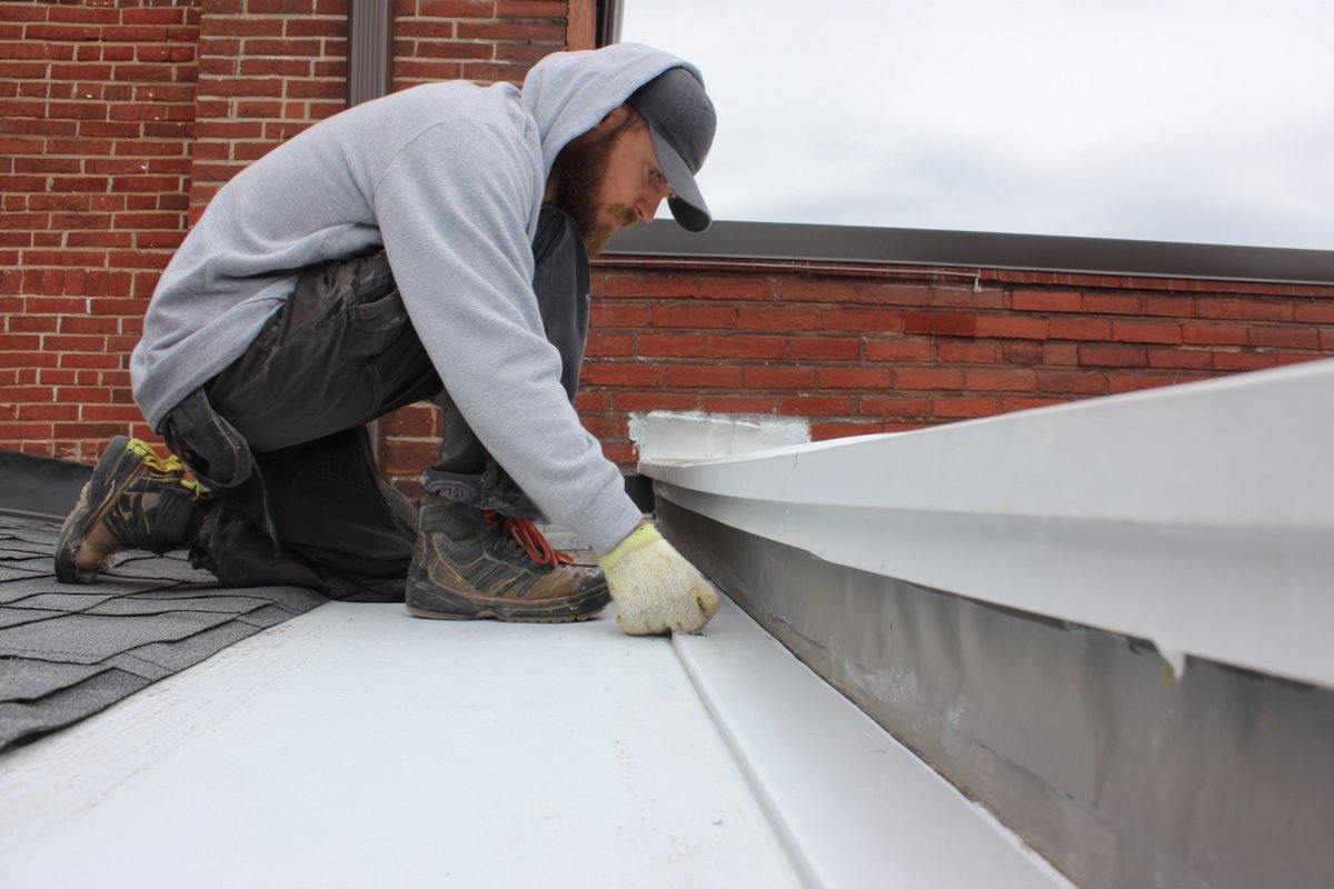 Close-up of new base flashing turned up a brick back wall, with counter-flashing set into a reglet above, where a kitchen extension roof meets the house