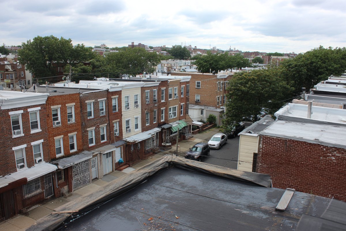 Wide view of a Queens rowhouse block with flat roofs and parapet walls
