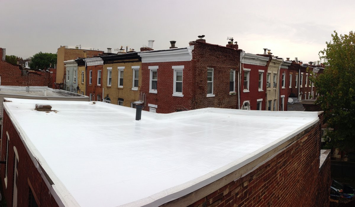 New 60-mil TPO roof with heat-welded seams on an attached brick row house in Astoria