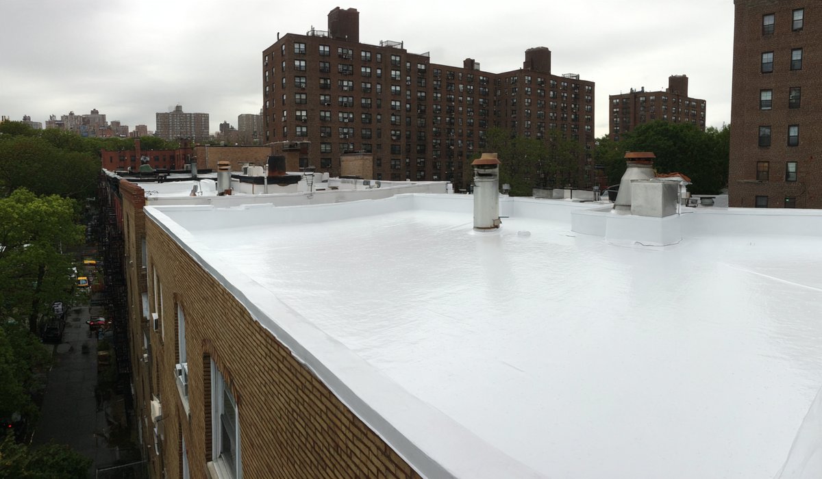 Bright white silicone roof coating over the membrane of a six-unit apartment building in Forest Hills