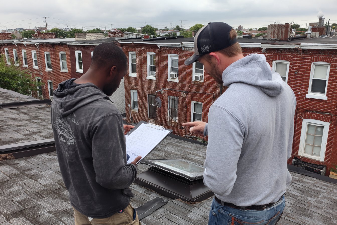 Flat Roofers NY estimator going over an itemized roof quote with a homeowner on a Queens row house