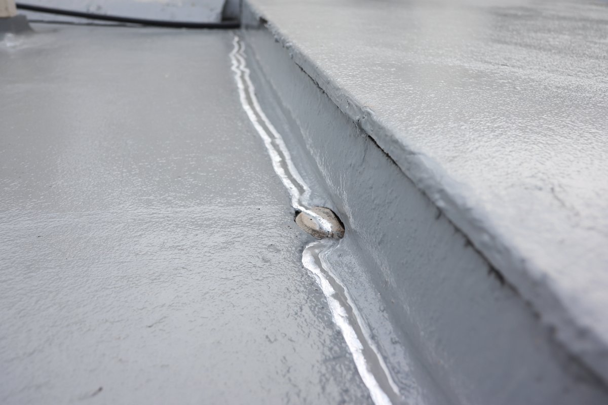 Close-up of a resealed seam and new flashing at a roof drain on a Queens flat roof repair