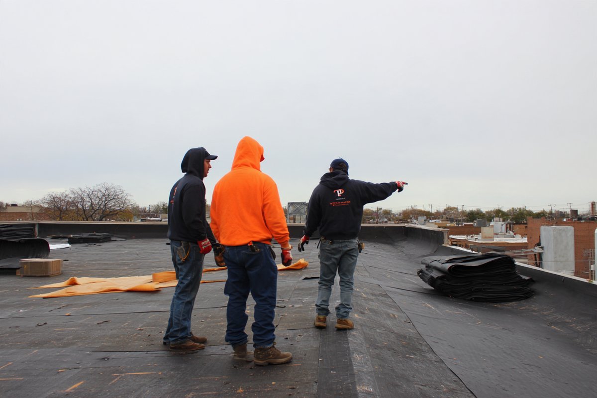 Flat Roofers NY crew on a Queens flat roof, the site lead going over the day's work before the tear-off