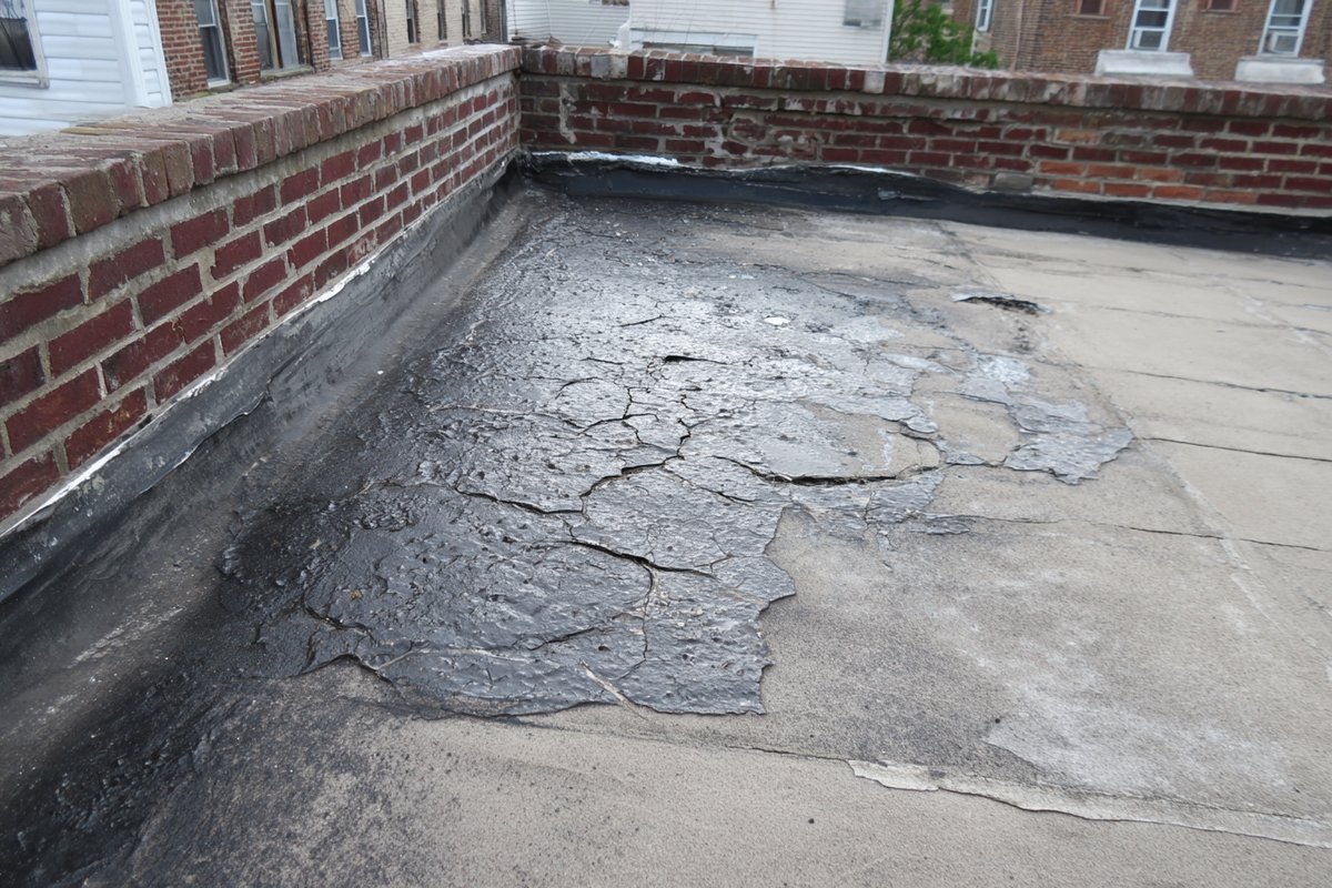 Finished modified bitumen repair on a Queens low-slope roof, the new cap sheet patch fused into the older roof around it