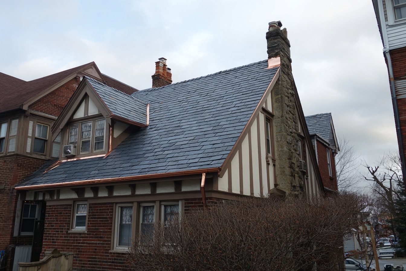 Finished natural slate roof with copper flashing on an older Tudor-style home in Queens
