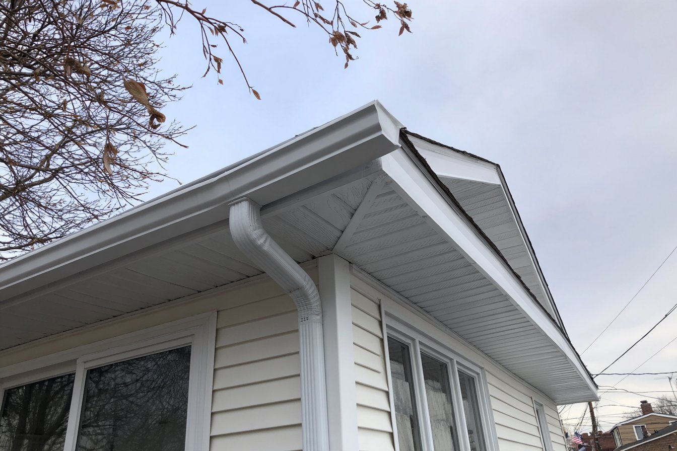 New white fascia board and vented soffit along the eaves of a Queens house, gutter rehung on the fresh trim