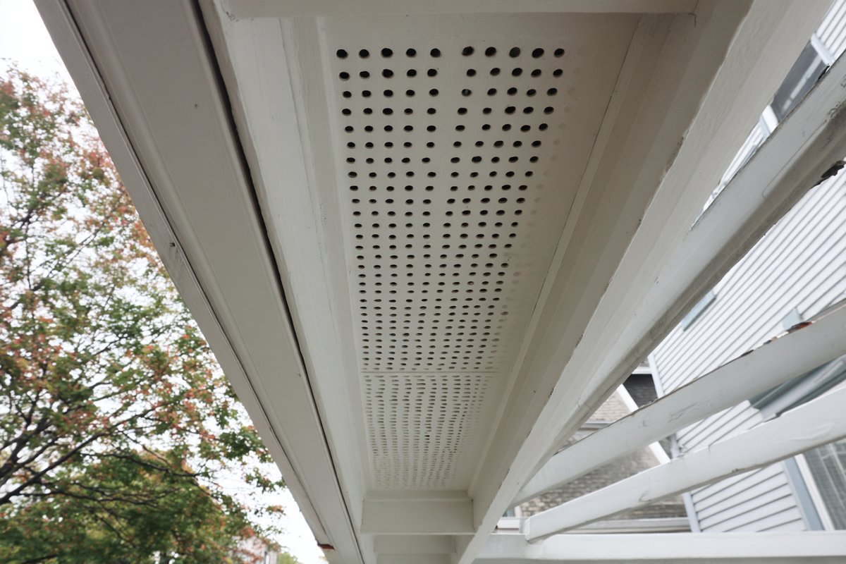 Close-up of a vented soffit panel installed under a roof overhang, perforations open to the attic